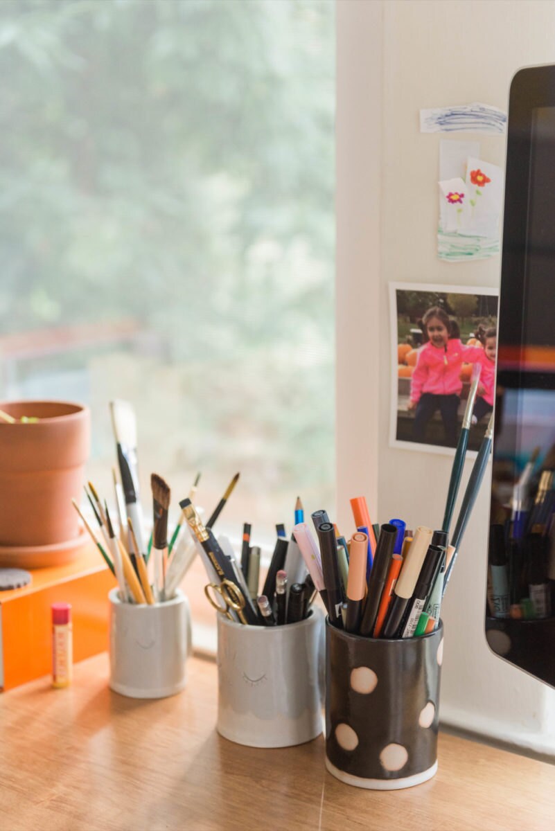 Meenal's tools organized on her desk, including pens, markers, pencils, and paintbrushes