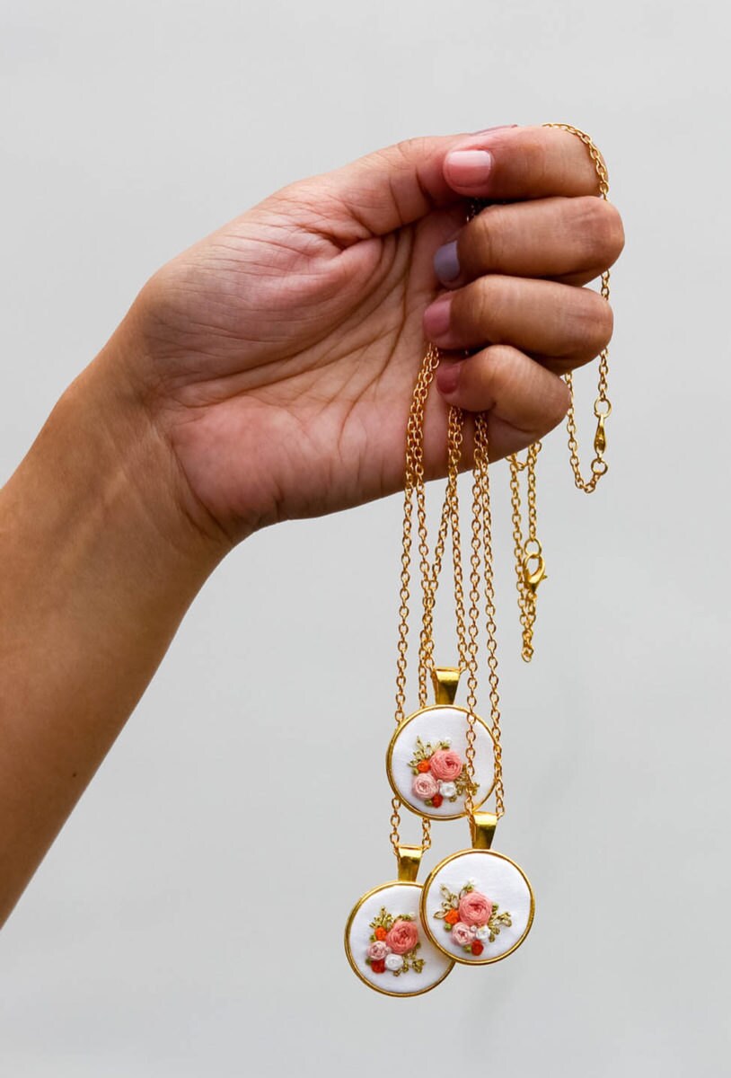 Three matching embroidered floral necklaces set in circular gold pendants from Thursday Craft Love