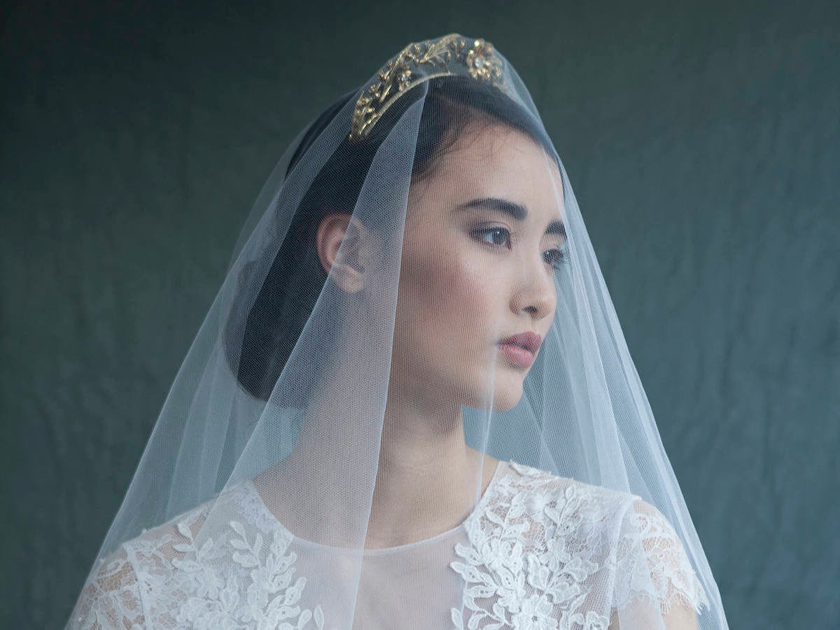 Woman modeling a gold bridal headpiece and veil from Agnes Hart