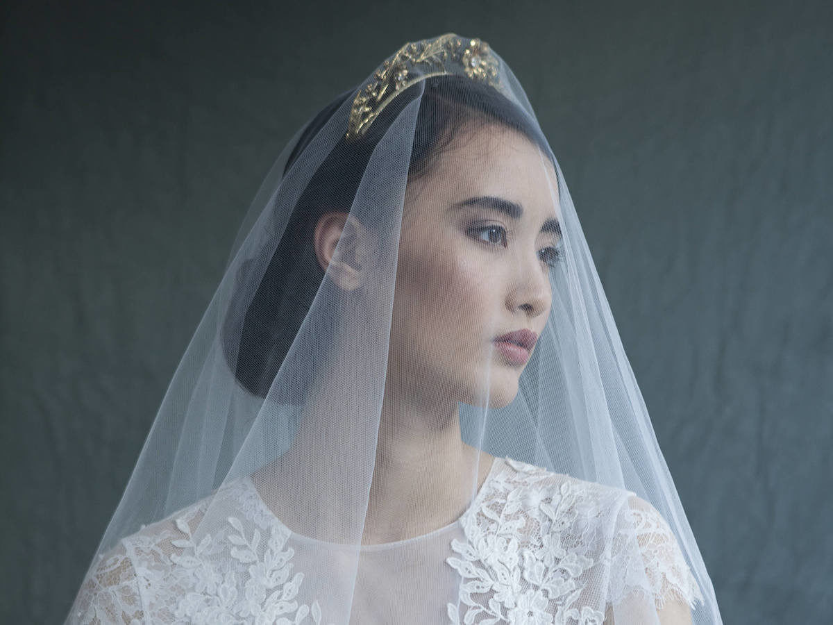 Woman modeling a gold bridal headpiece and veil from Agnes Hart