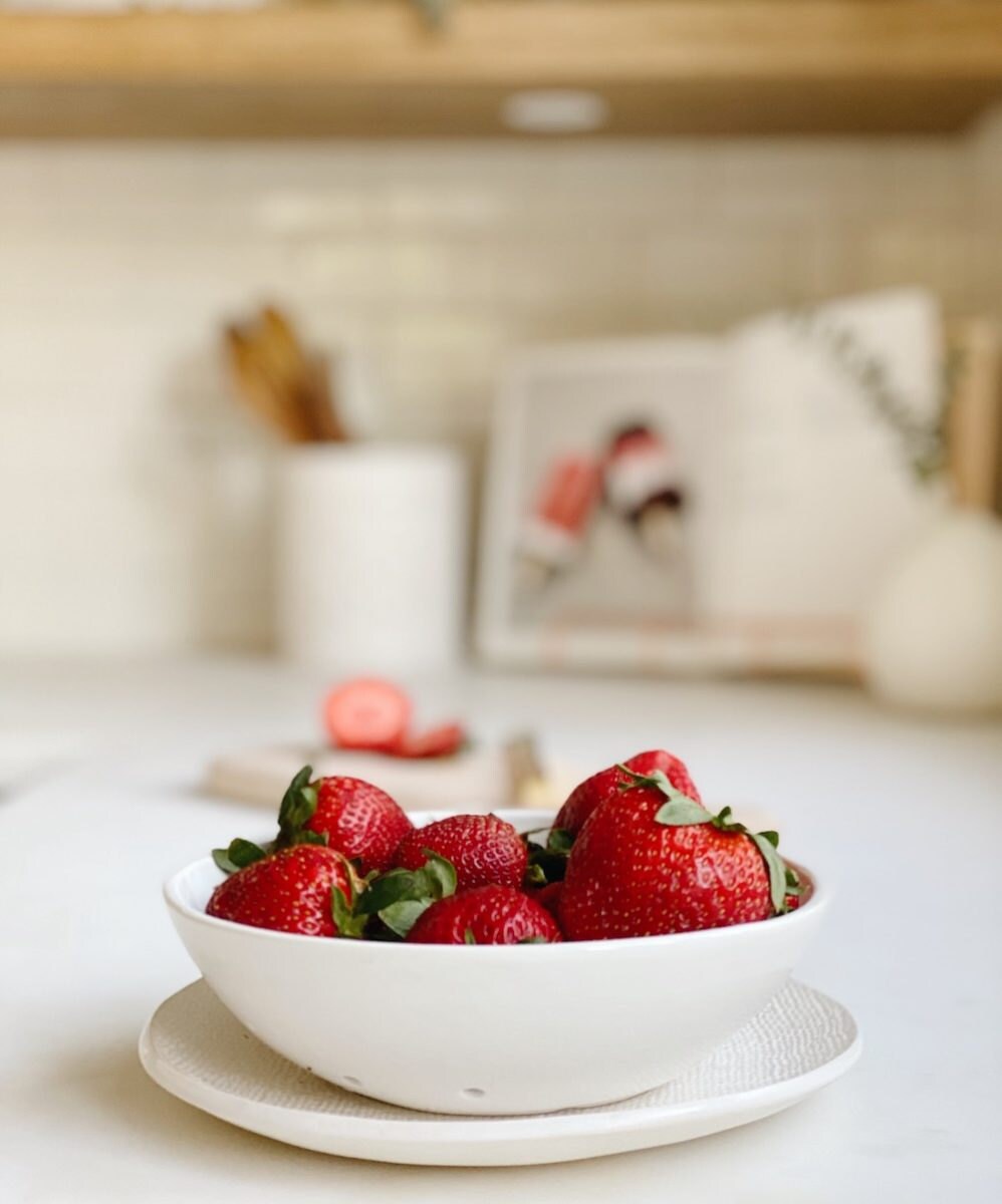 A ceramic berry bowl from lookslikewhite, holding a fresh batch of strawberries.