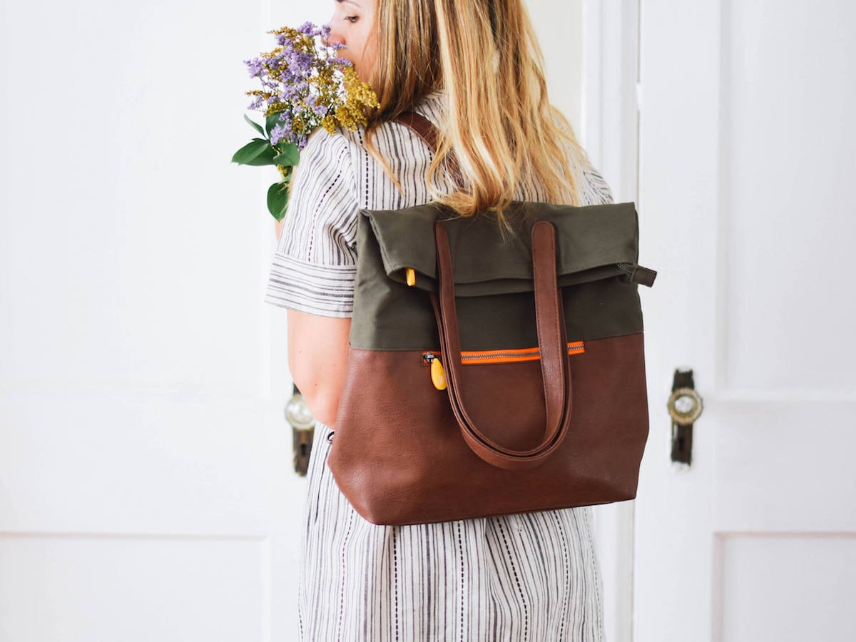 Woman wearing convertible vegan leather backpack from Canopy Verde in olive green and espresso.