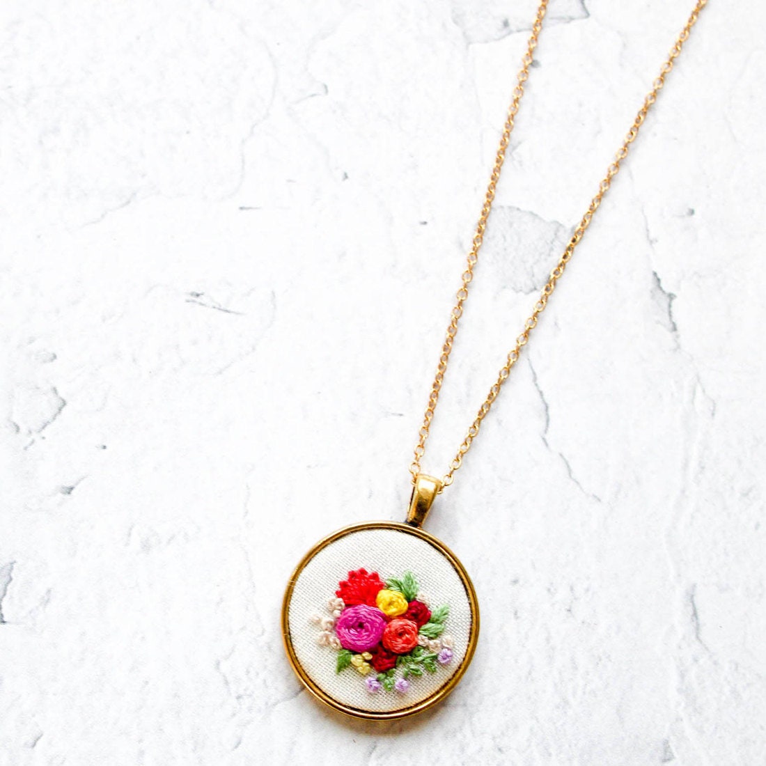 Vibrant floral embroidered necklace set in a circular gold pendant from Thursday Craft Love