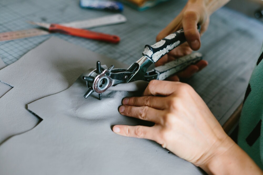 Alex punching holes into a piece of leather