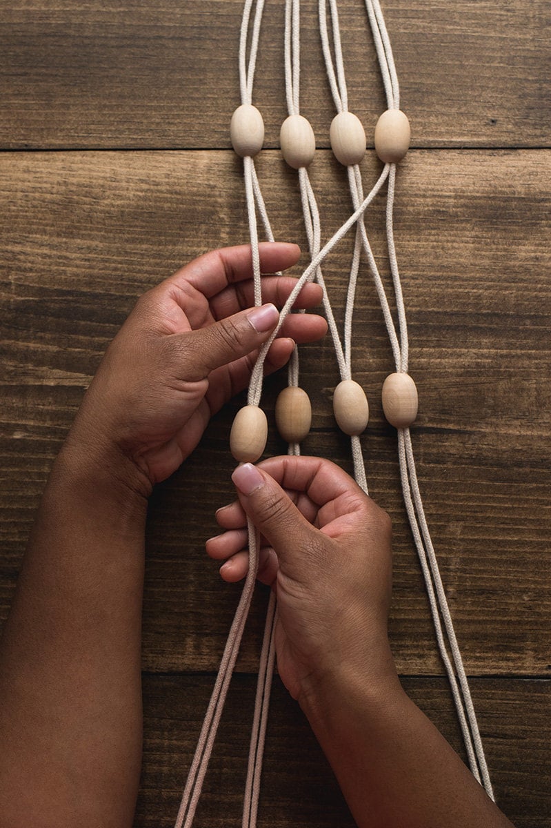 Hands separate the ropes and group into adjacent pairs, adding a bead to each.