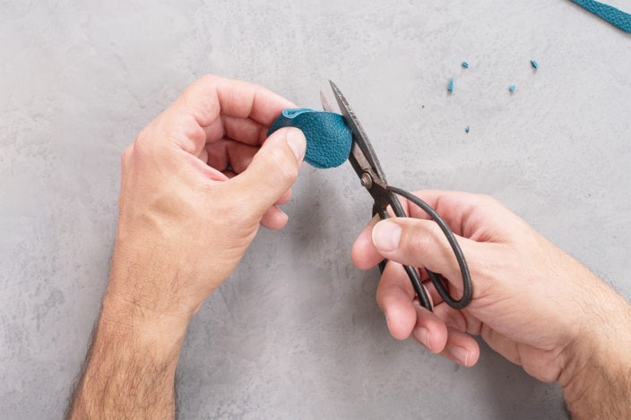 Edges of leather strip are rounded using steel shears