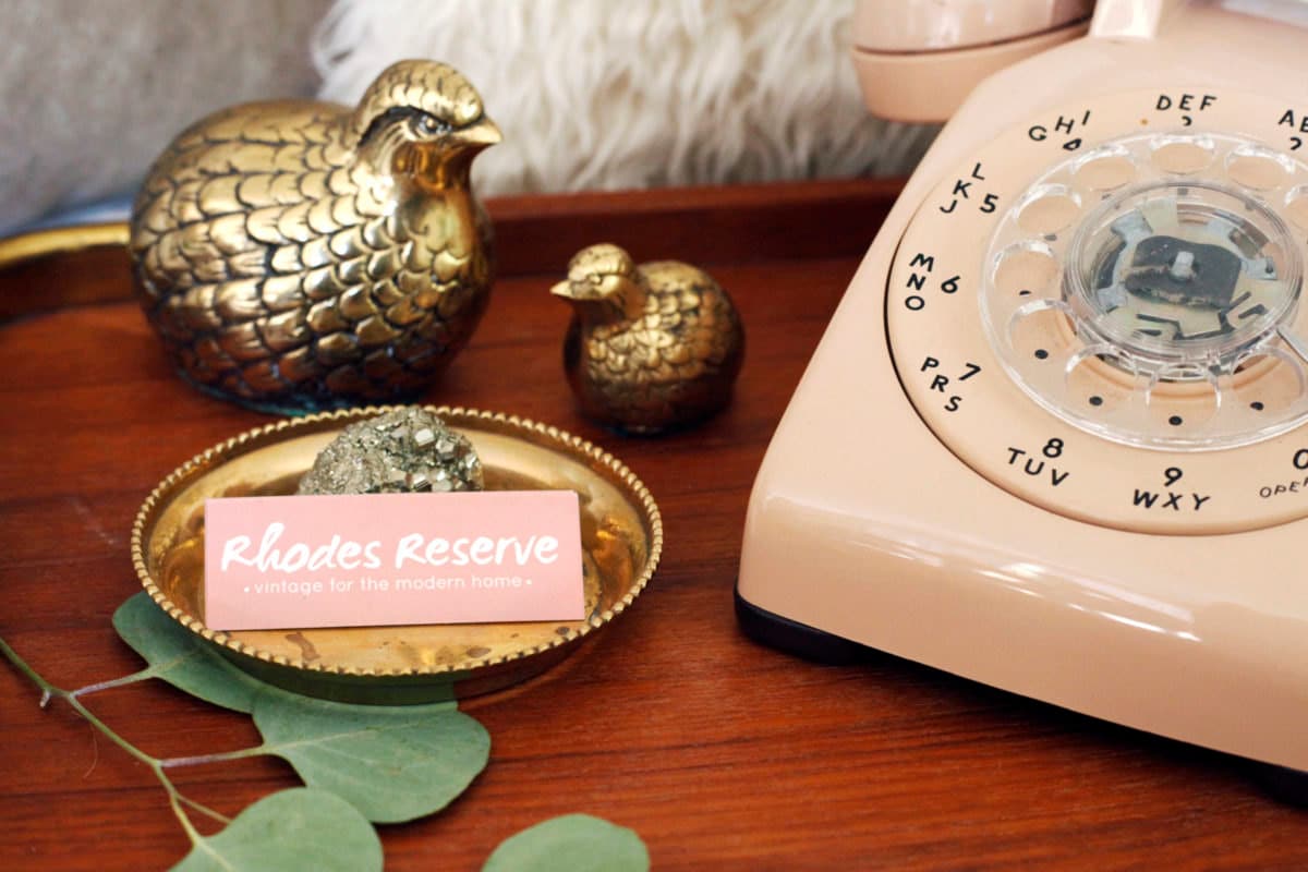 Brass birds, vintage phone, and Rhodes Reserve business cards arranged in Brenda's home