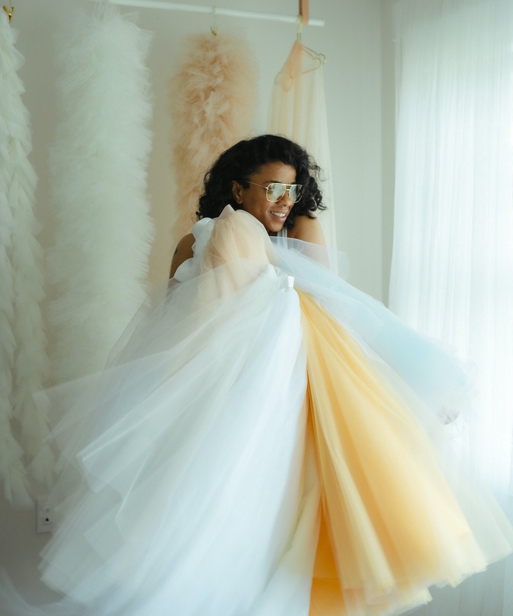 Keisha hugs a batch of colorful tulle fabric.