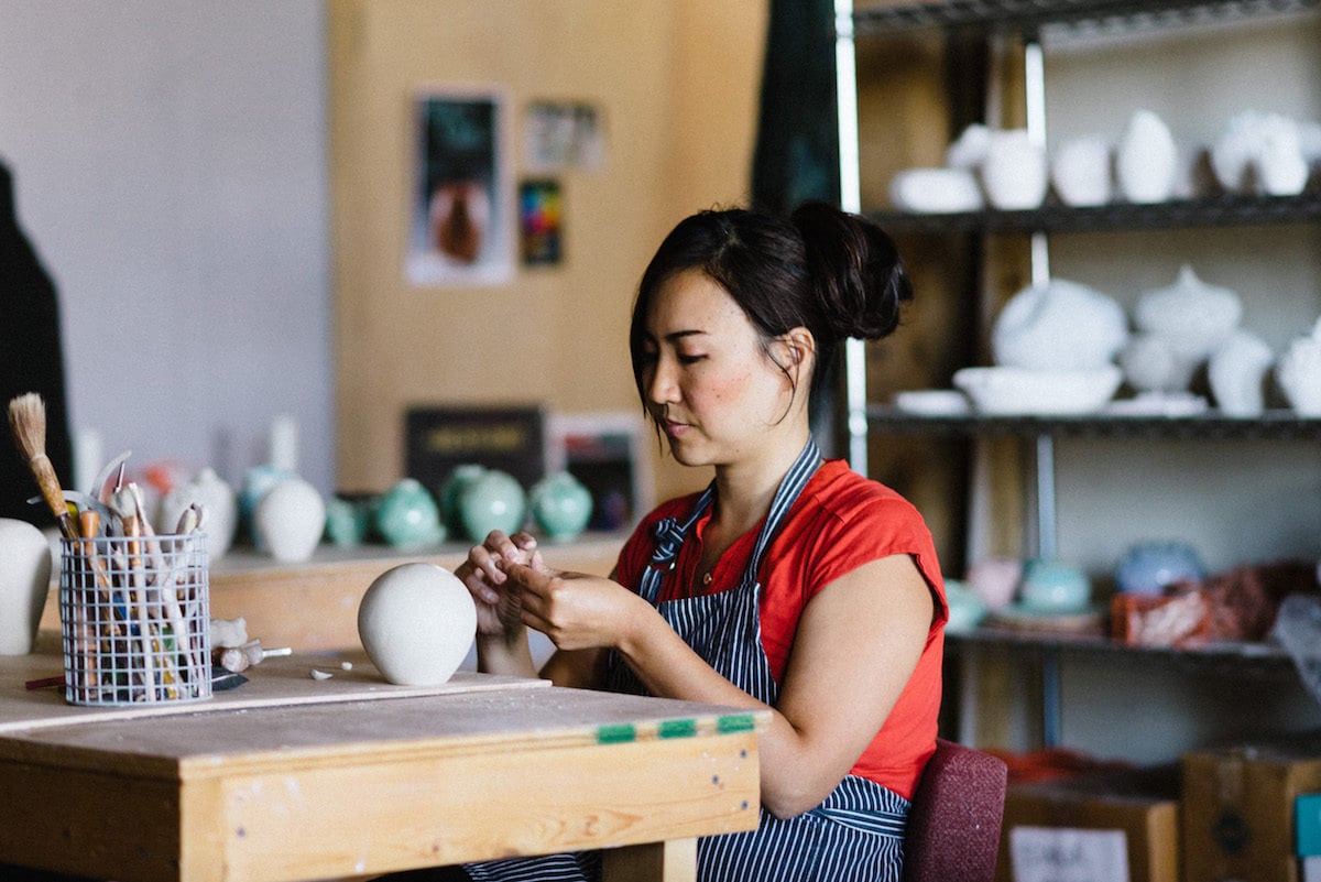 Yumiko at work in her studio, seated at her workbench