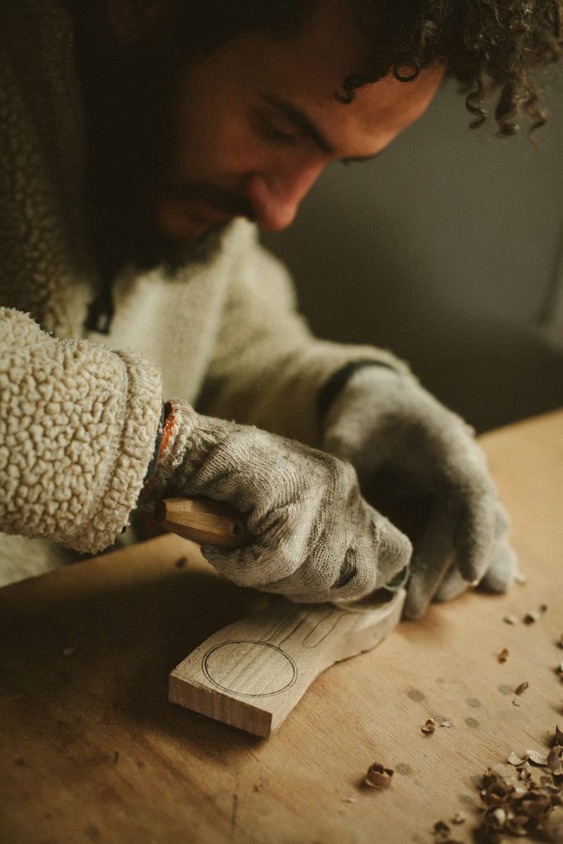 Kirill carves a spoon from a wooden block by hand