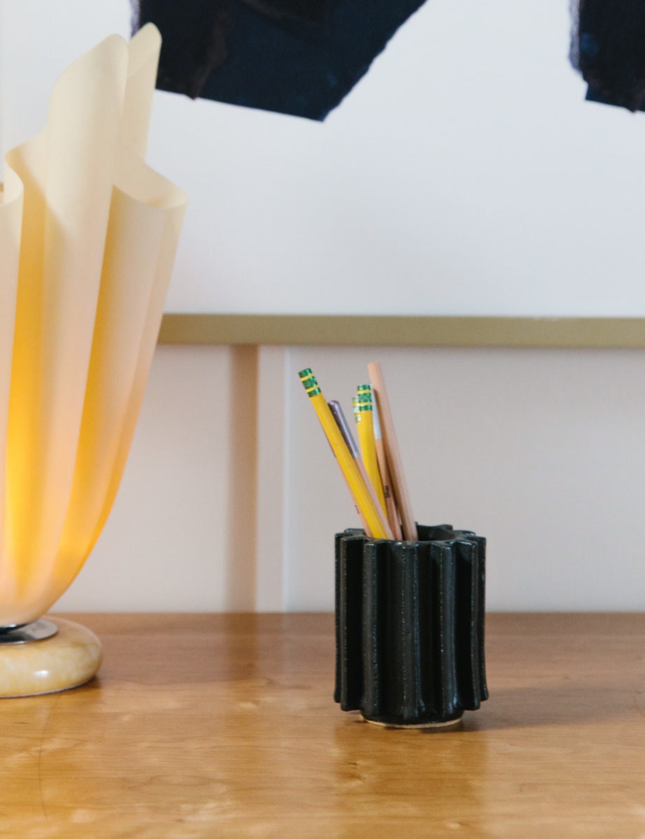 A ridged black ceramic cup with number two pencils inside.