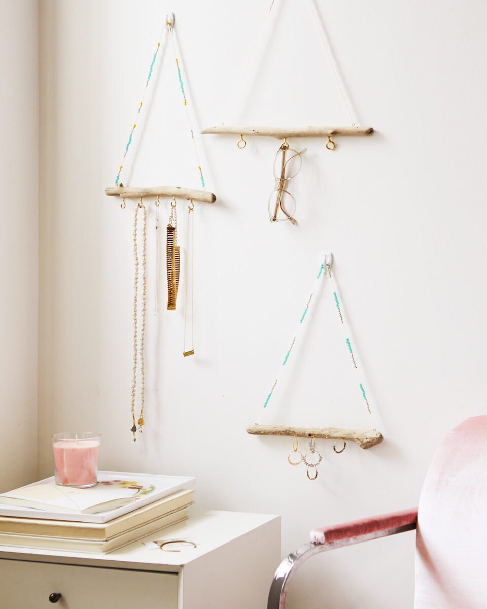 Three finished driftwood jewelry organizers on display on a wall