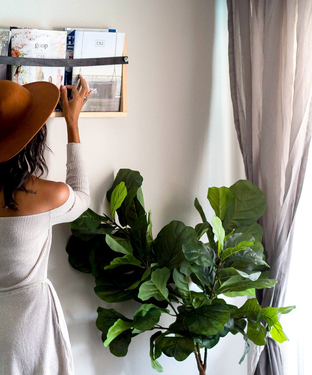 Ilana fills a wooden wall rack with magazine.