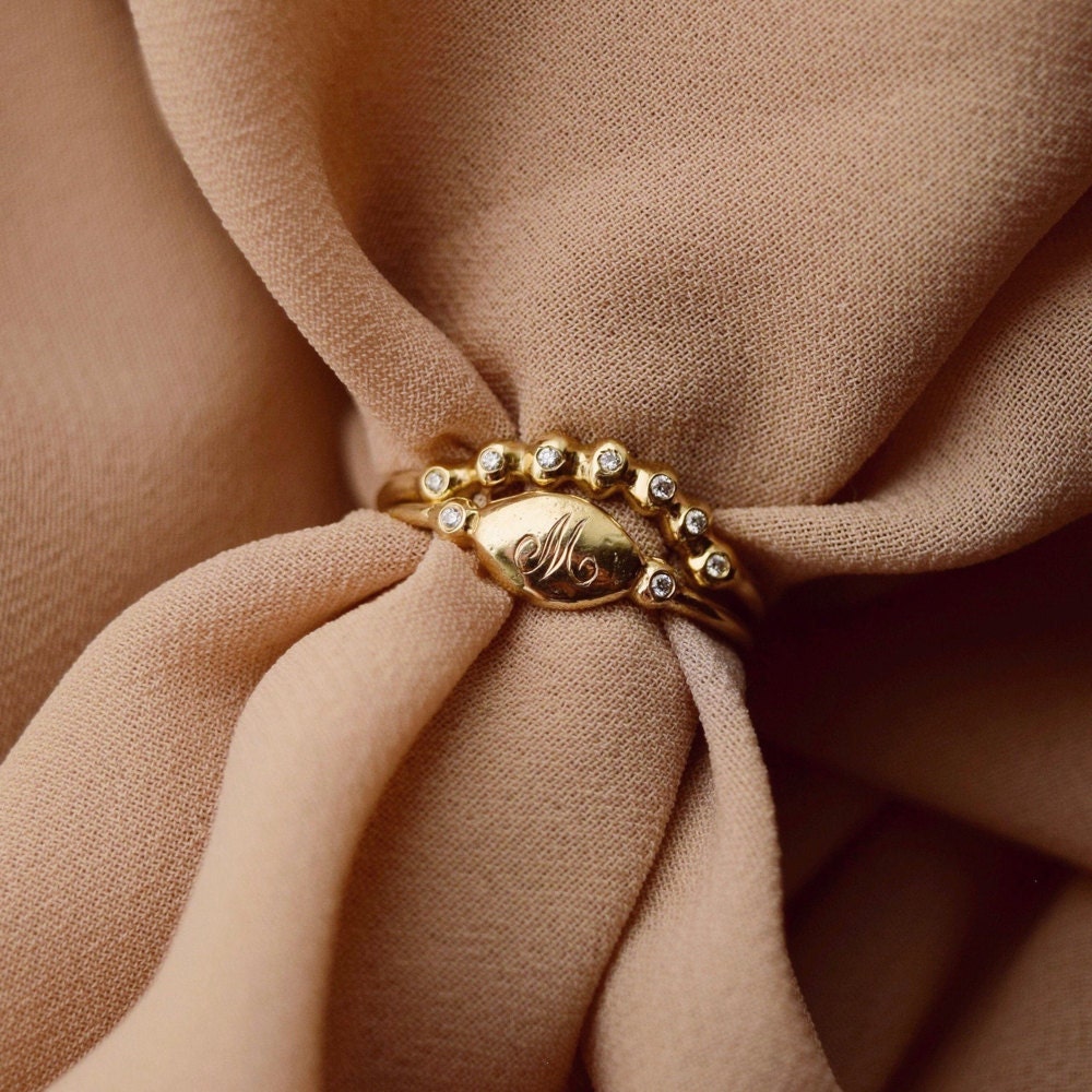 A curved diamond ring and initial signet ring from Everli