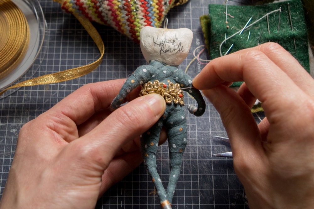 Kayleigh sews an outfit onto her bear ornament