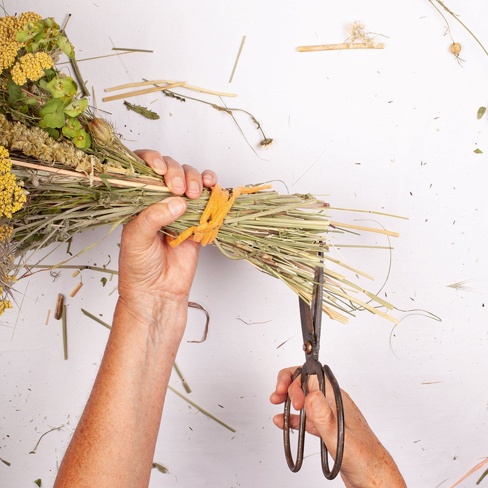 A person completes the final step—trimming the ends of the stems