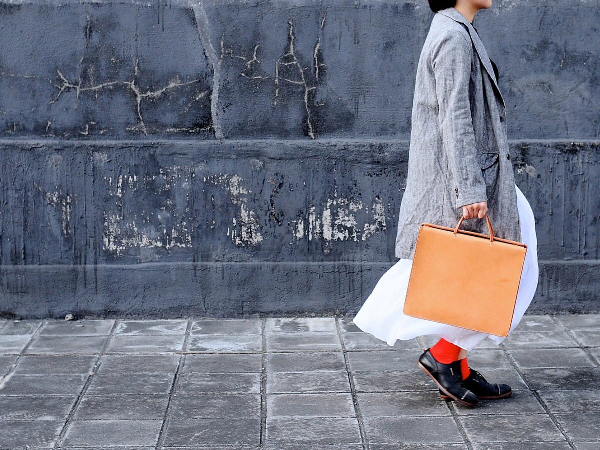 Model carrying a square tan leather bag from Artemis Leatherware