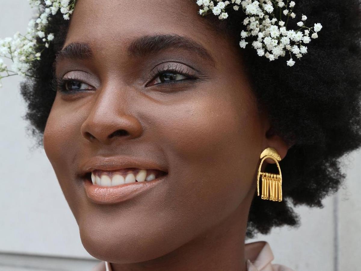 Woman modeling brass dangle statement earrings from Lingua Nigra