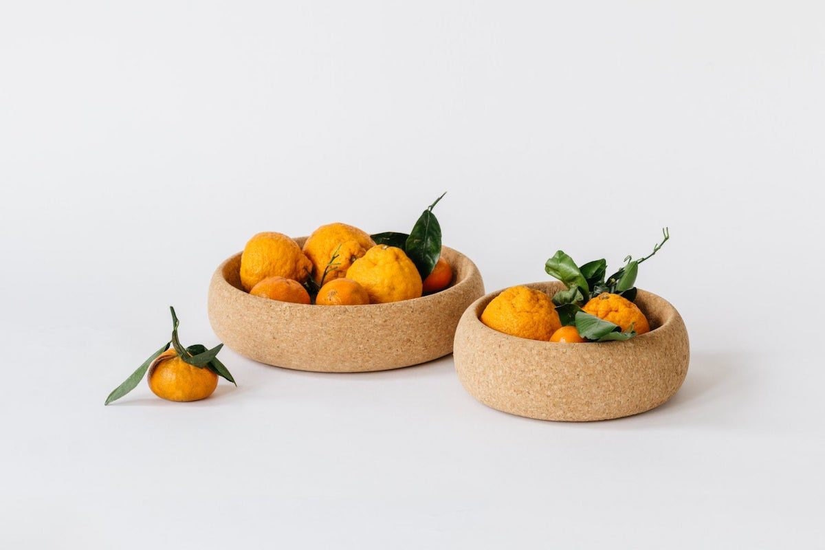 Two round cork bowls holding clementines