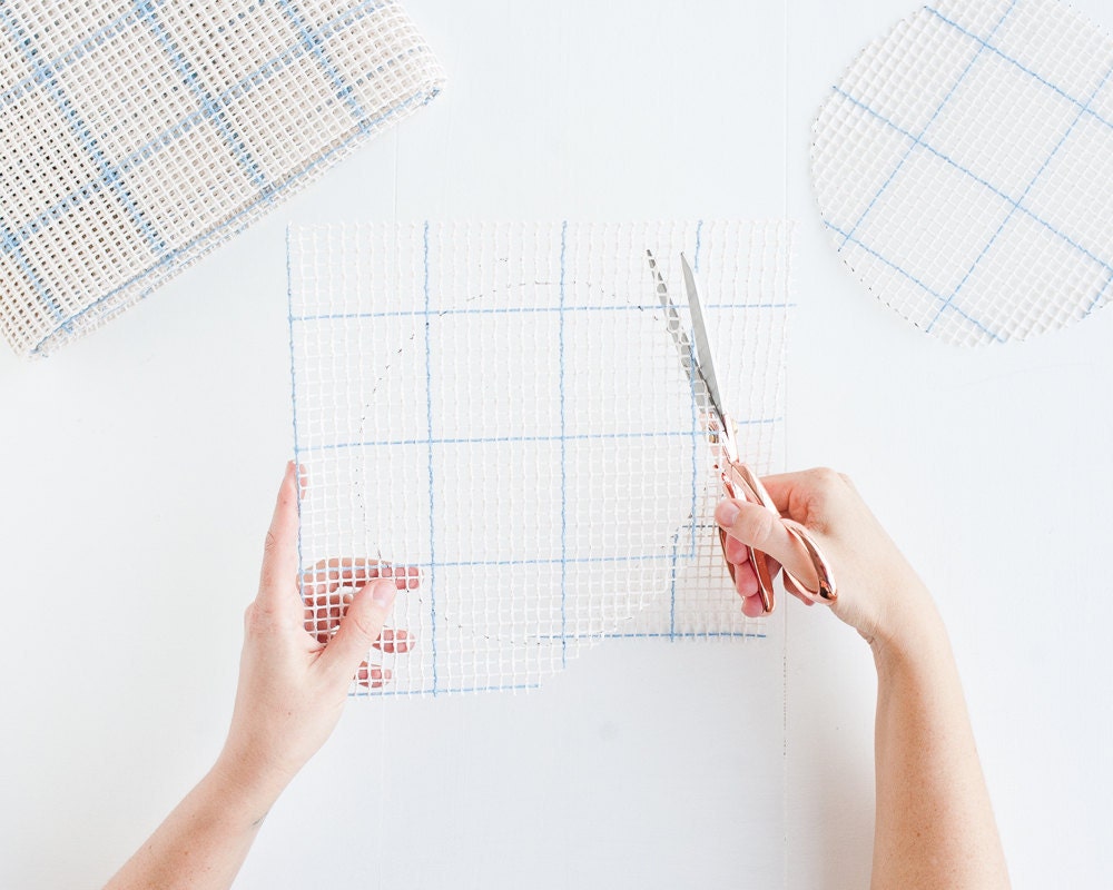 Cutting two traced circles out of rug canvas