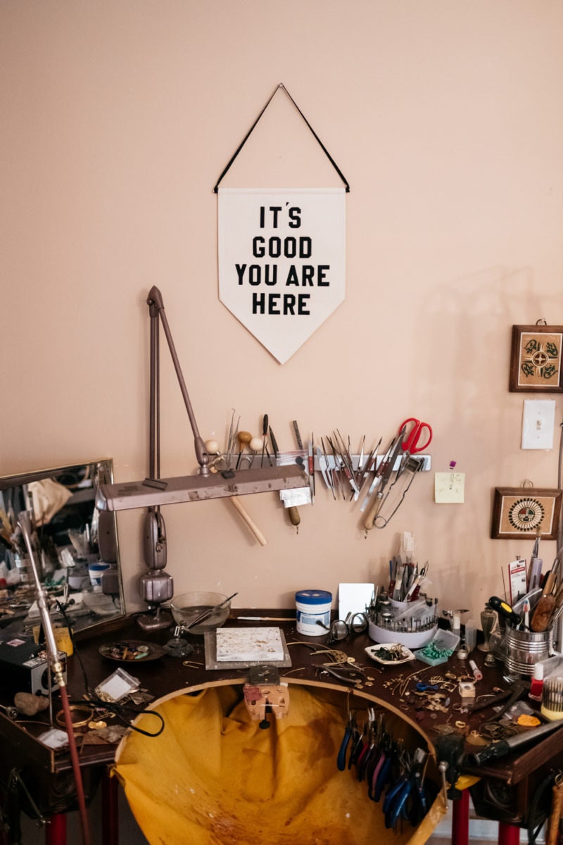 Alicia's metal-smithing station, decorated with a pendant that reads "It's Good You Are Here"