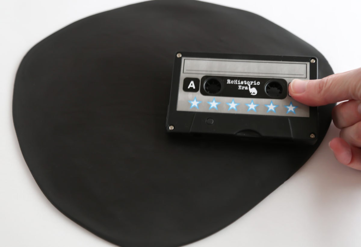Heather uses a cassette tape to create impressions in a rolled out piece of fondant.