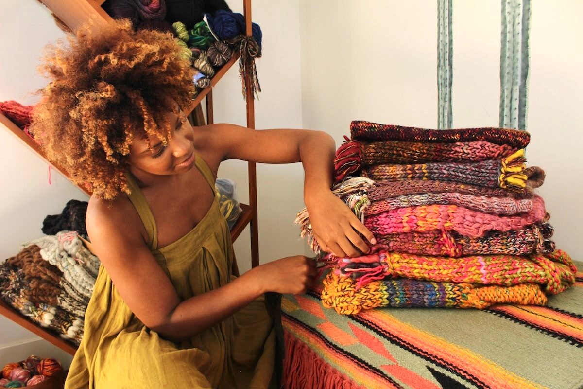 Chasten looking through a pile of folded knitwear in her home