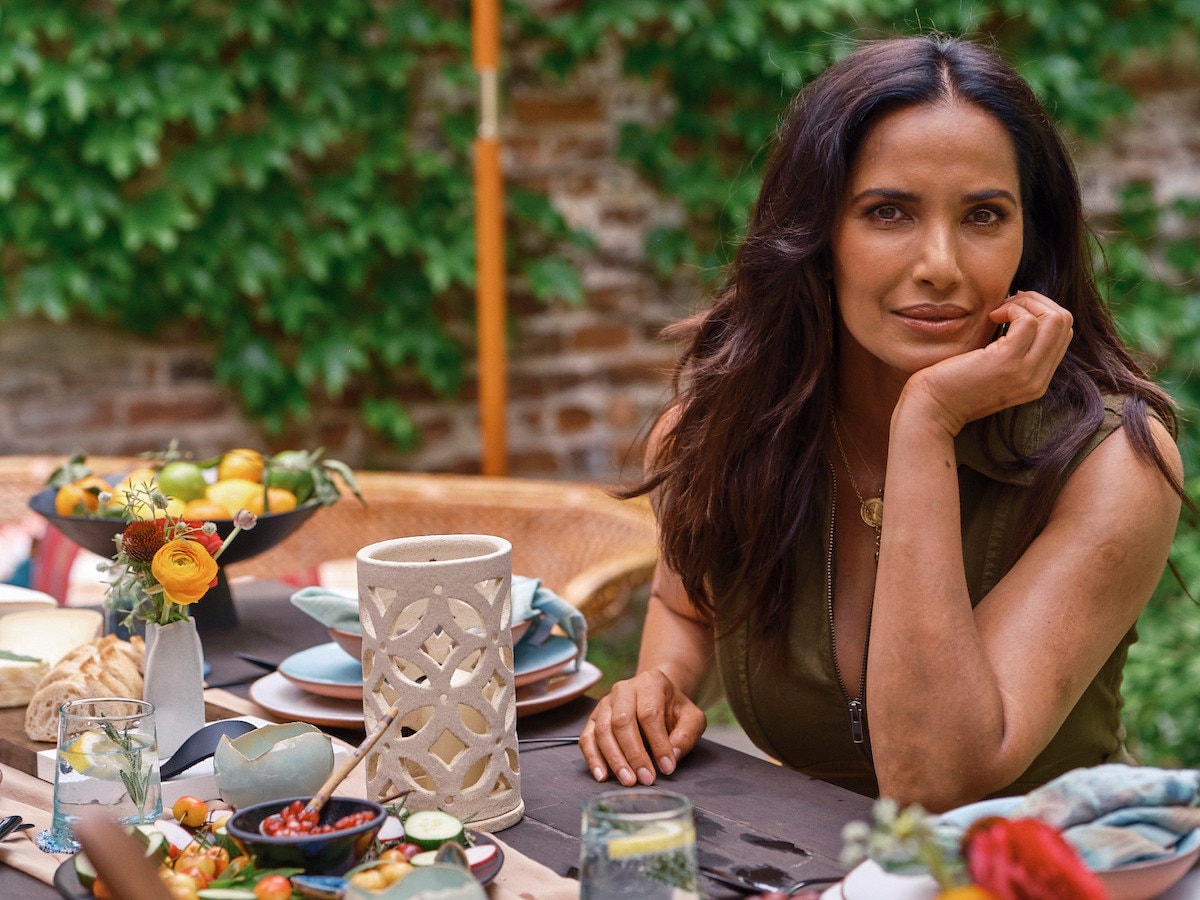 Padma Lakshmi sits at a set table