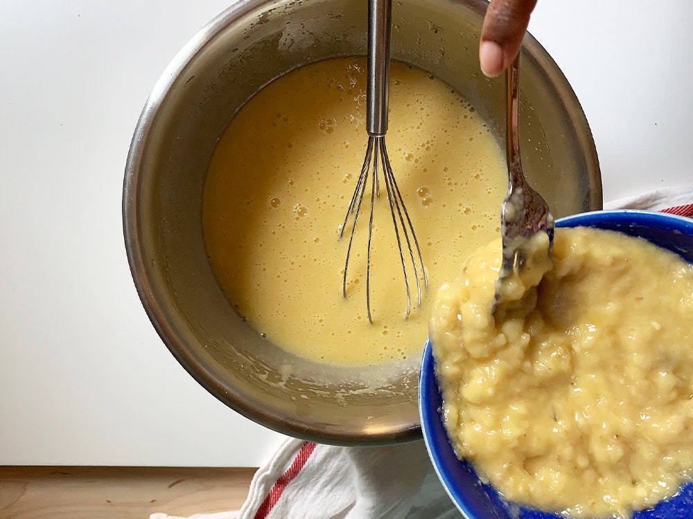 Aravis adding mashed banana to wet ingredients.