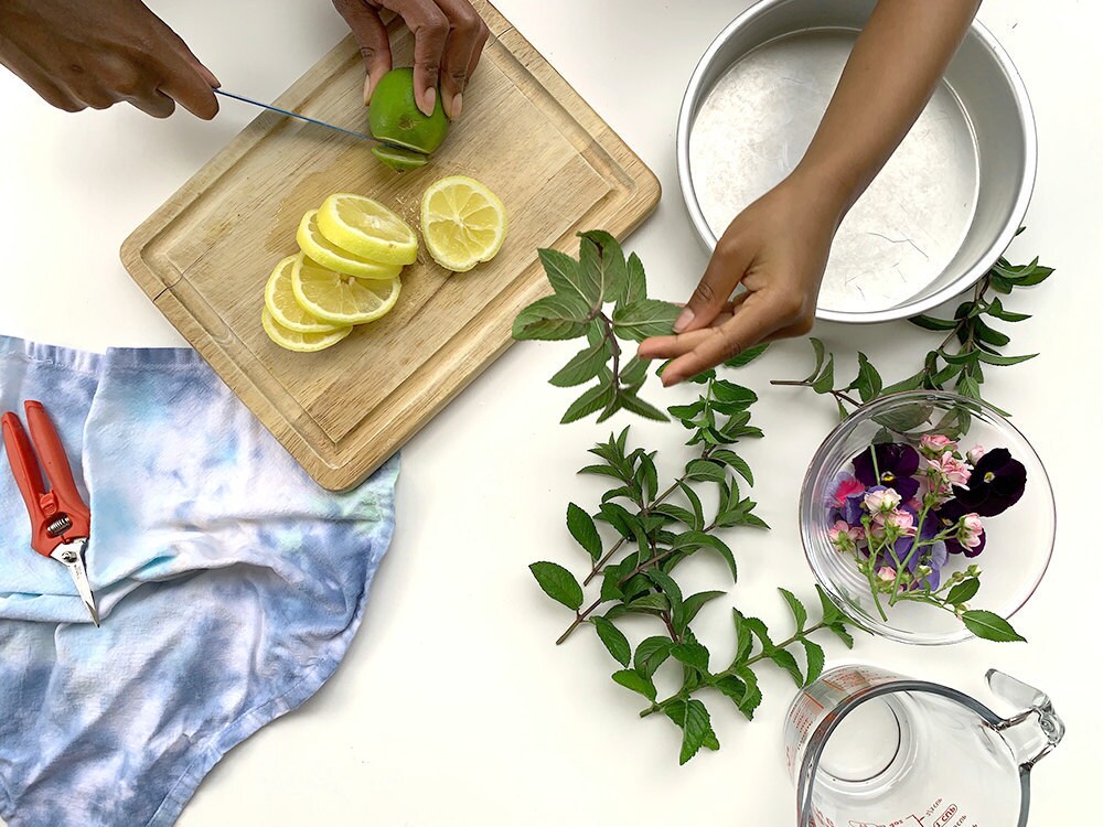 Aravis slices lemons and limes while her niece pulls mint leaves off their stems.