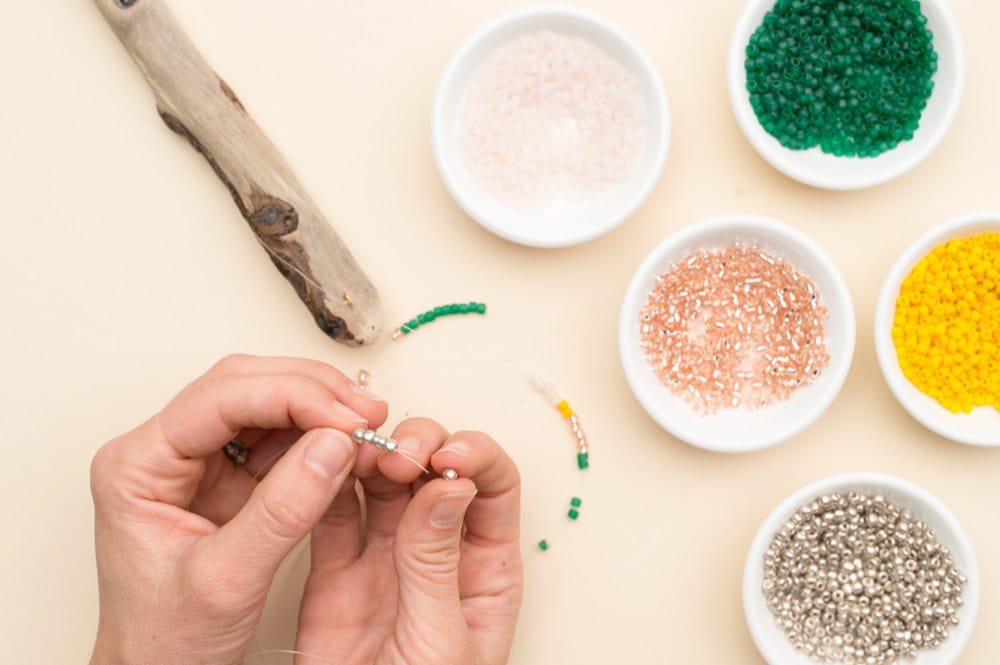 Stringing colorful seed beads onto the fishing line