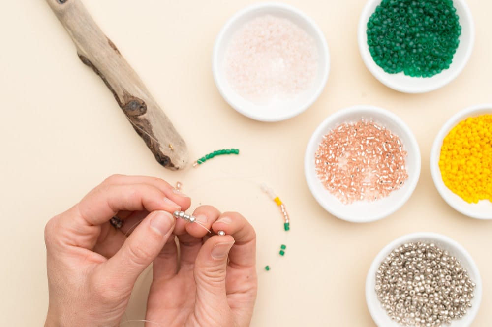 Stringing colorful seed beads onto the fishing line