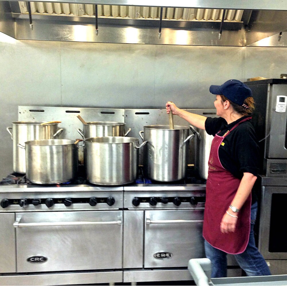 Adriana stirs an oversized pasta pot in her industrial kitchen