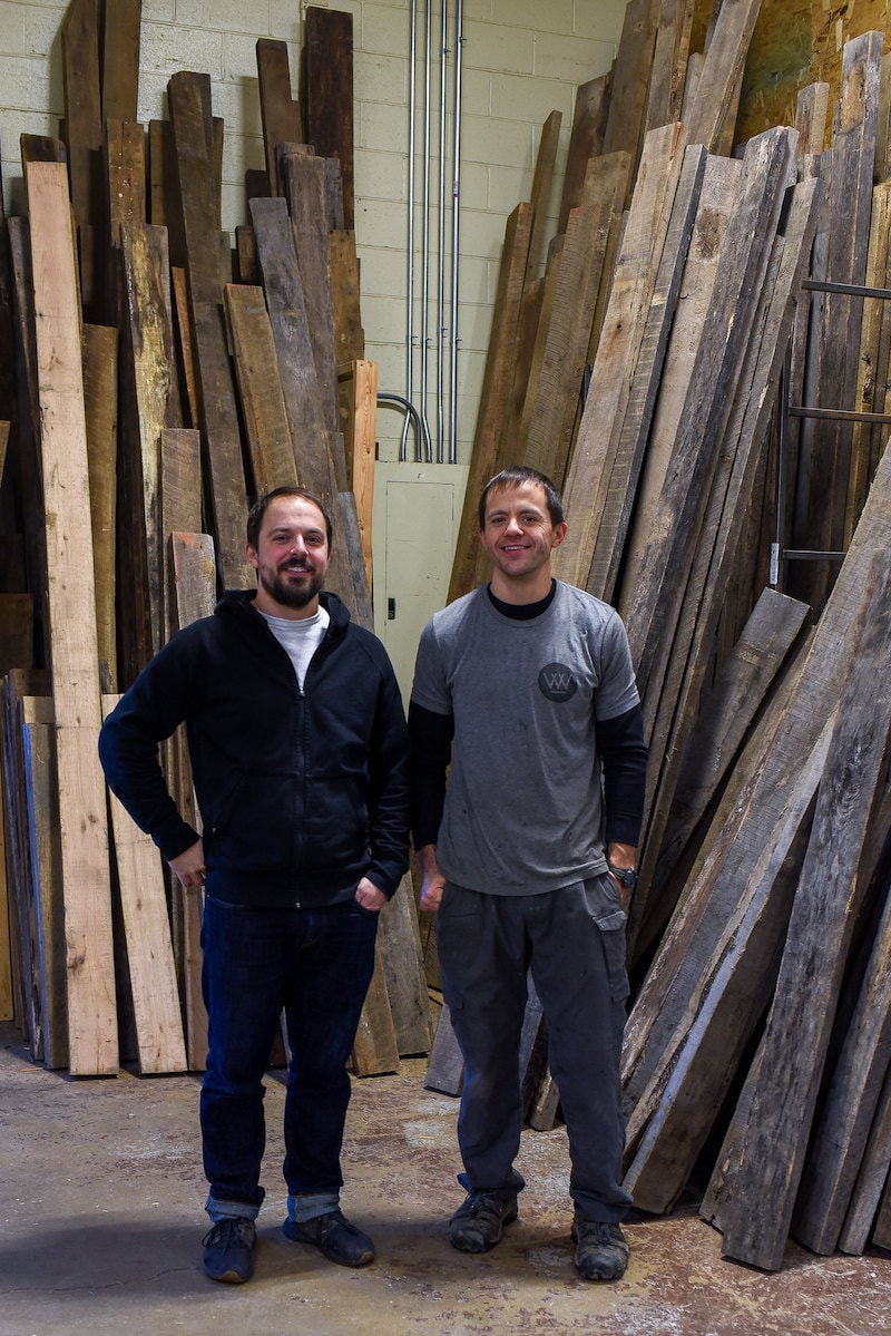 Dan and George standing in front of a collection of reclaimed wood