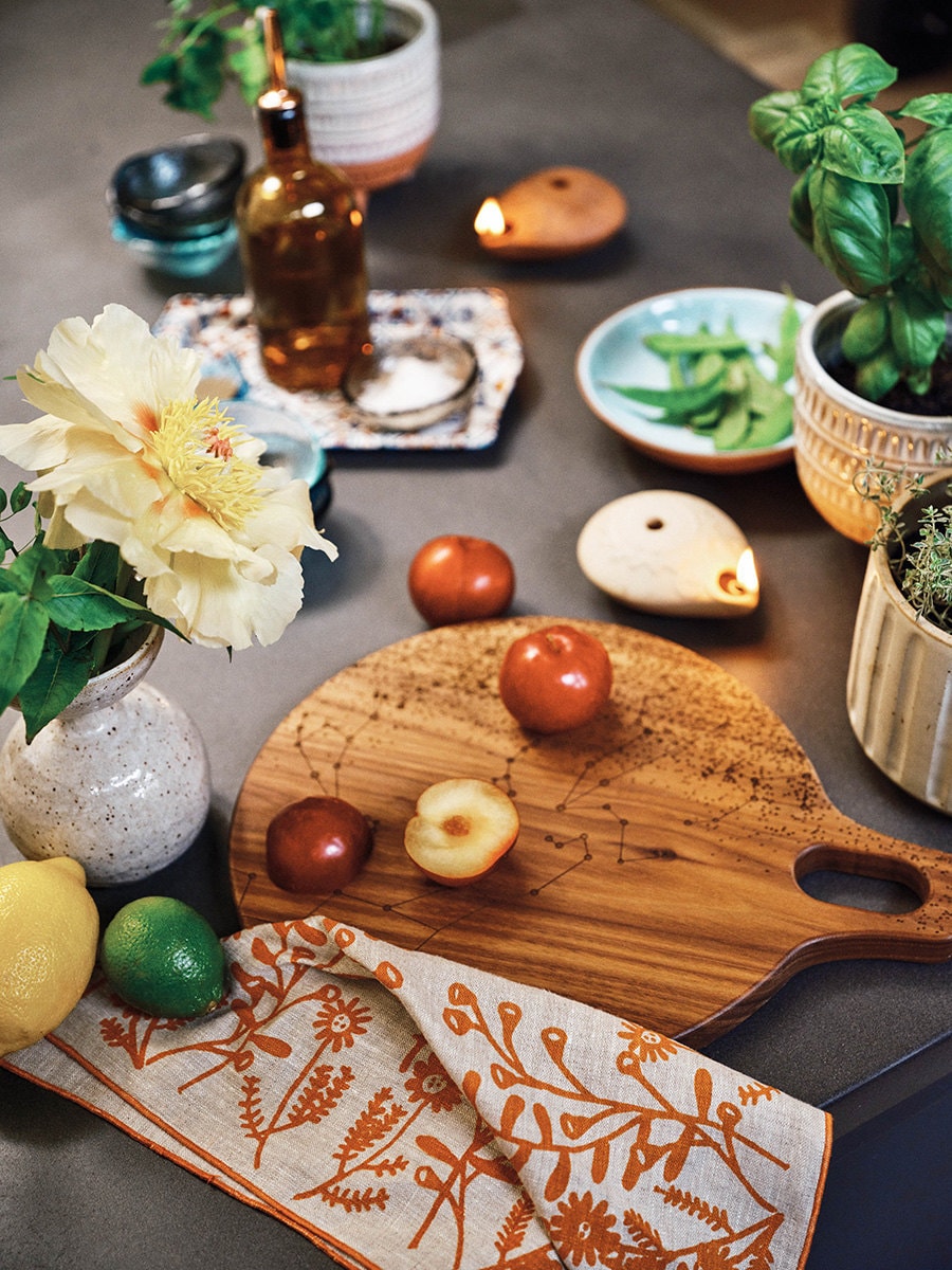 A kitchen counter scene featuring a constellation cutting board with fruit on top