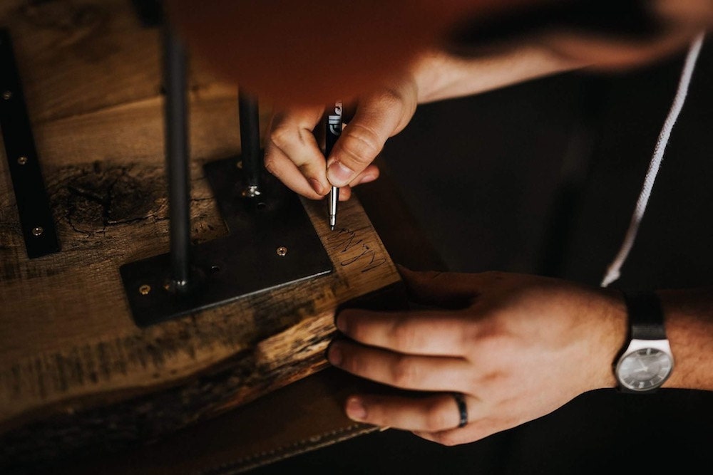 A CBYMCREATIVE woodworking puts a finishing touch on a piece