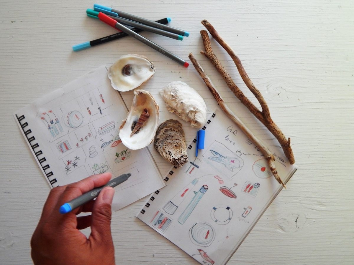 Edith sketches new designs in a notebook