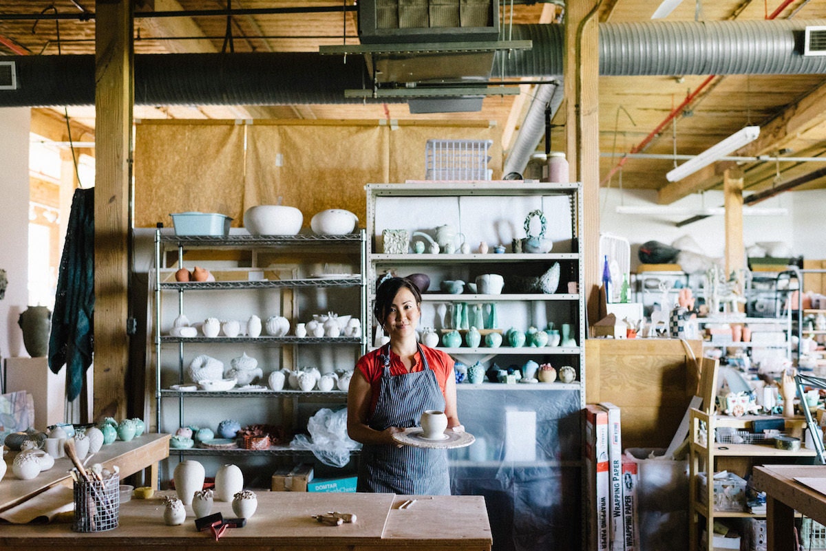 Yumiko holds a piece of pottery-in-progress