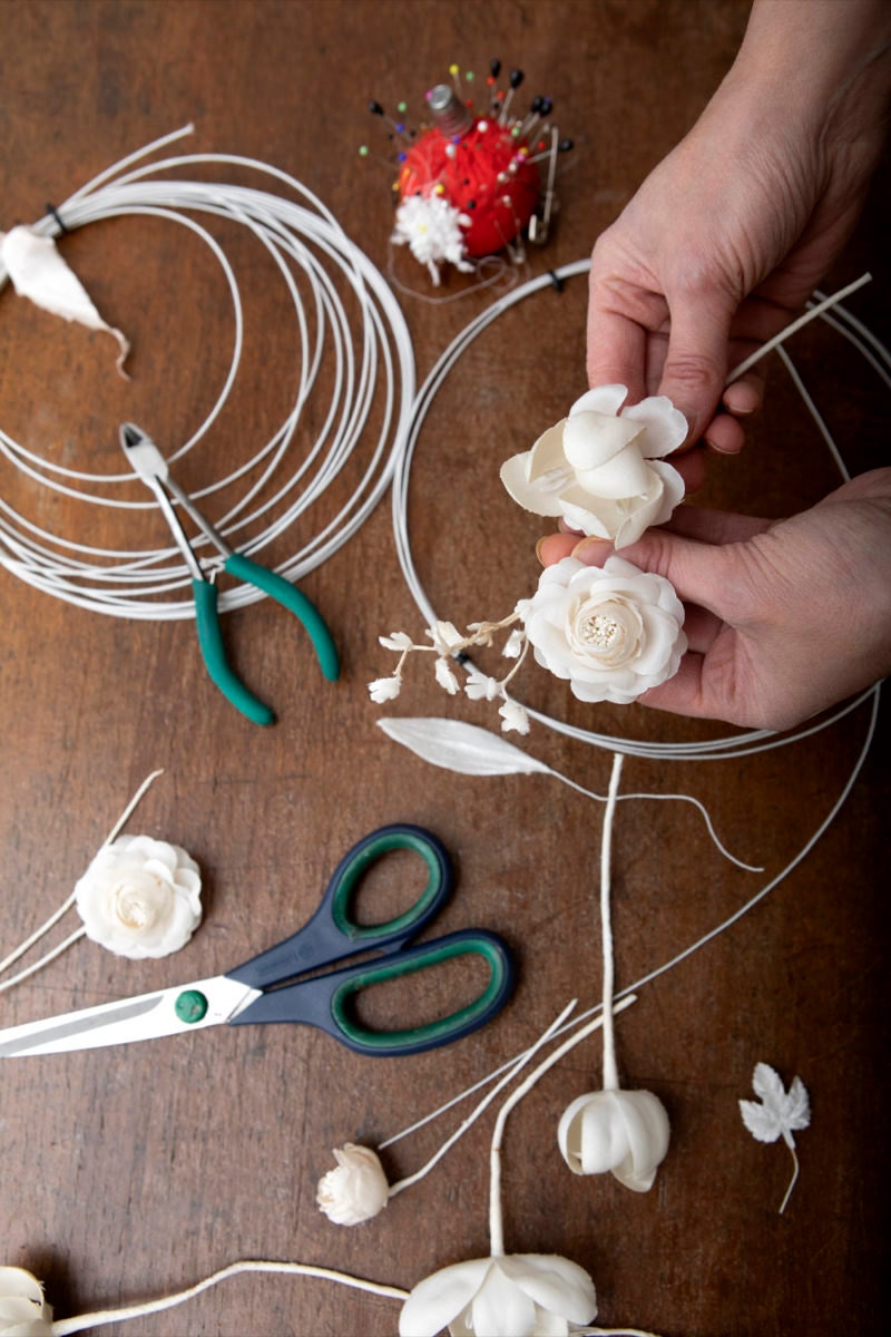 Rae attaches silk roses to a wire base to create a floral crown.