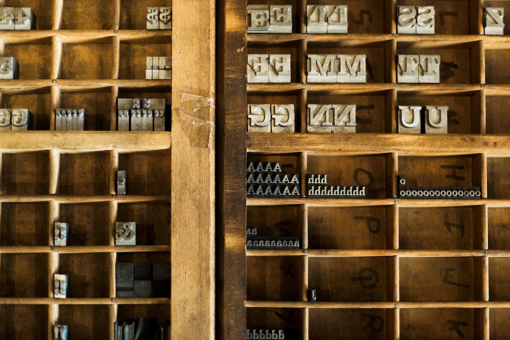 A neatly organized shelf containing a variety of letter stamps in different sizes and styles.