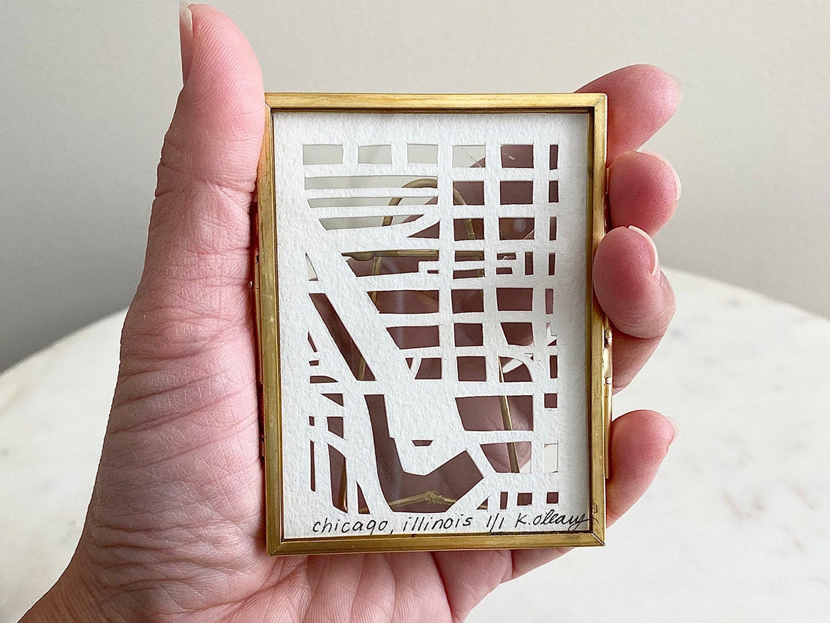 A model holds a miniature hand-cut map of Chicago, Illinois.