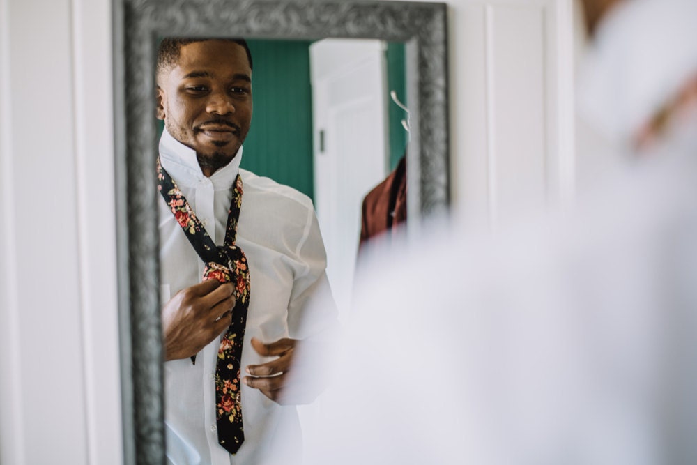 A reflection of Terrell putting on his tie in the mirror