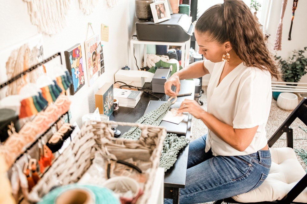 Casey works on finishing a macrame plant hanger in her home studio.