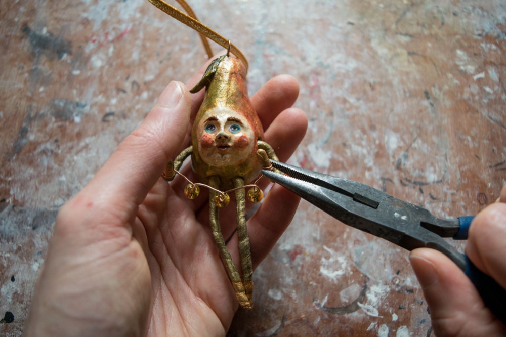 Kayleigh adds a tiny bell collar to her gold pear ornament
