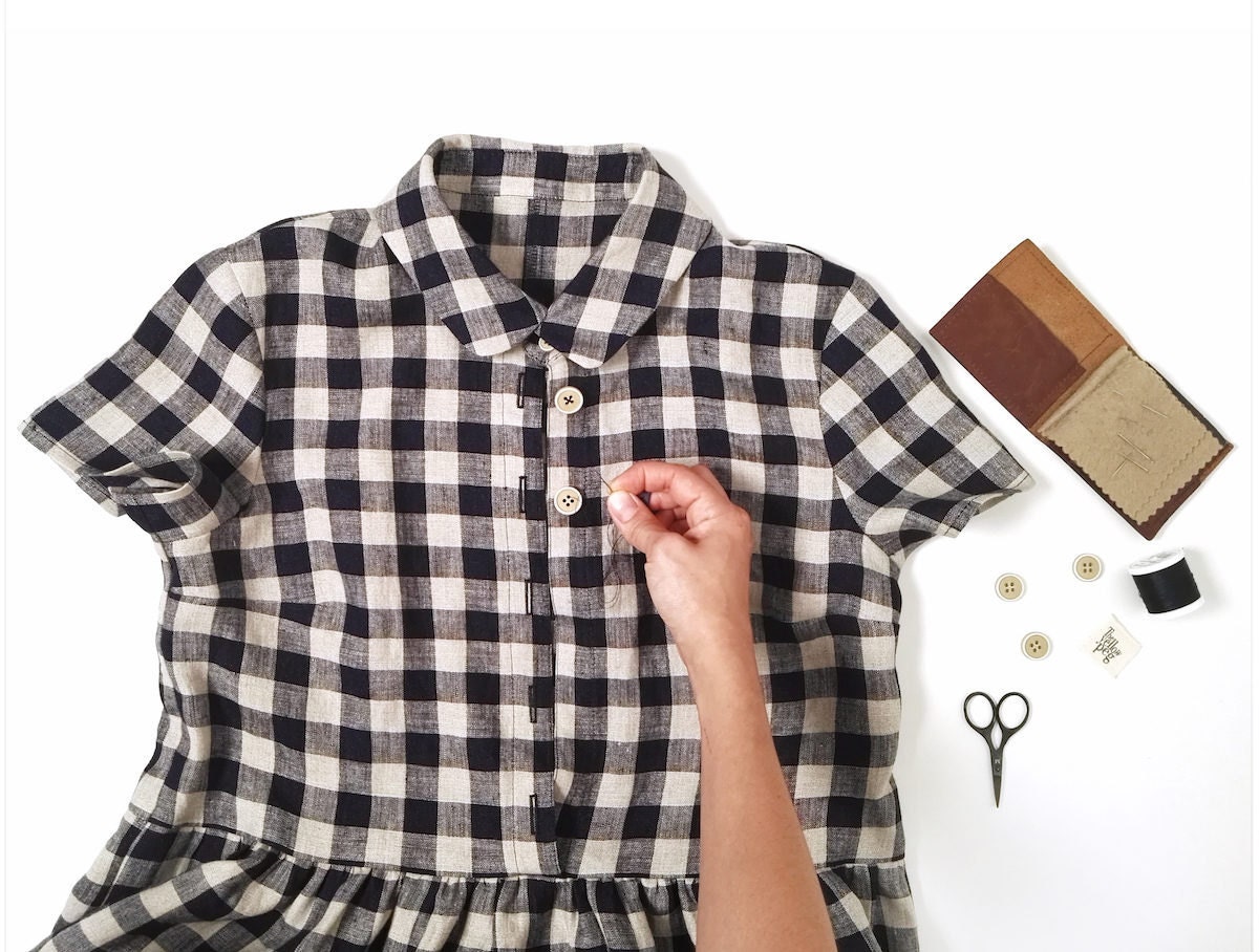 Close-up shot of Simona hand-sewing a black and white gingham dress