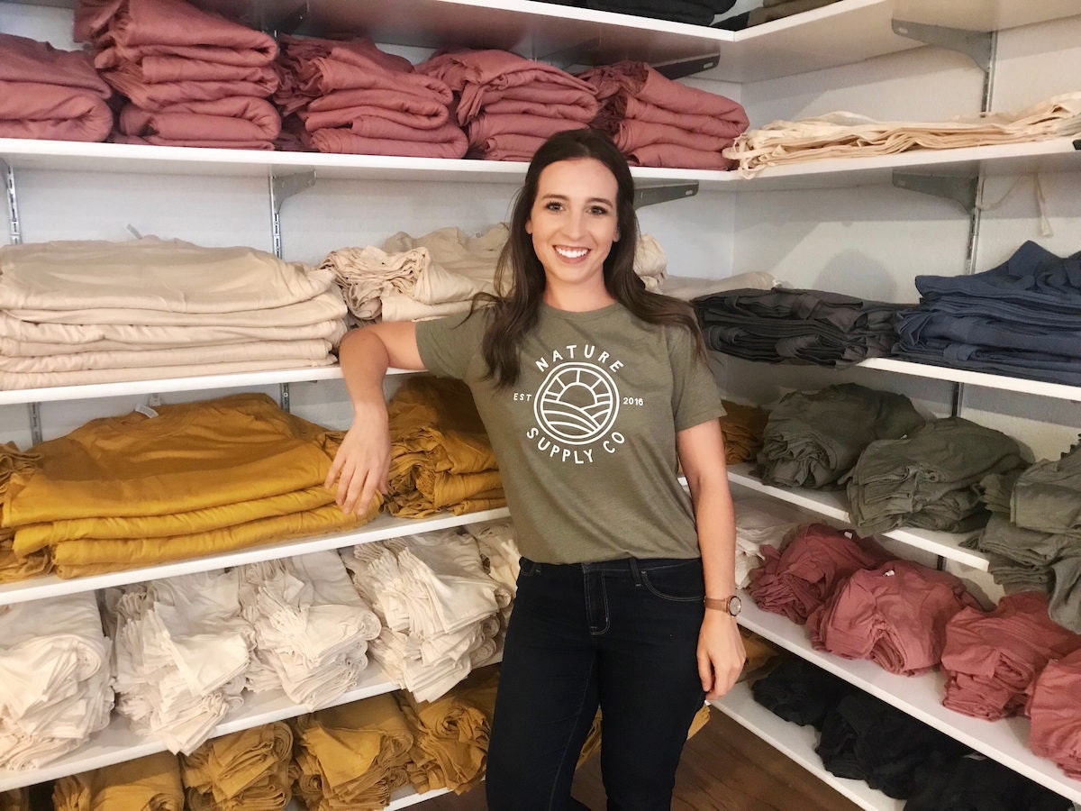 Lindsey poses with blank T-shirts and tote bags in her basement studio