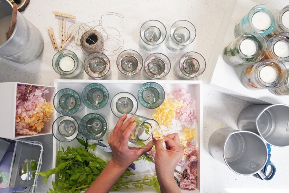 Rino arranges dried flowers in her decorative glass candle bases.