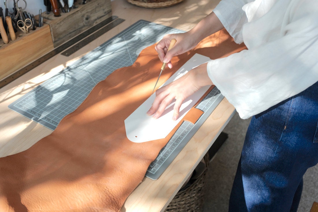 Quynh cuts around a bag template using a hand-held blade