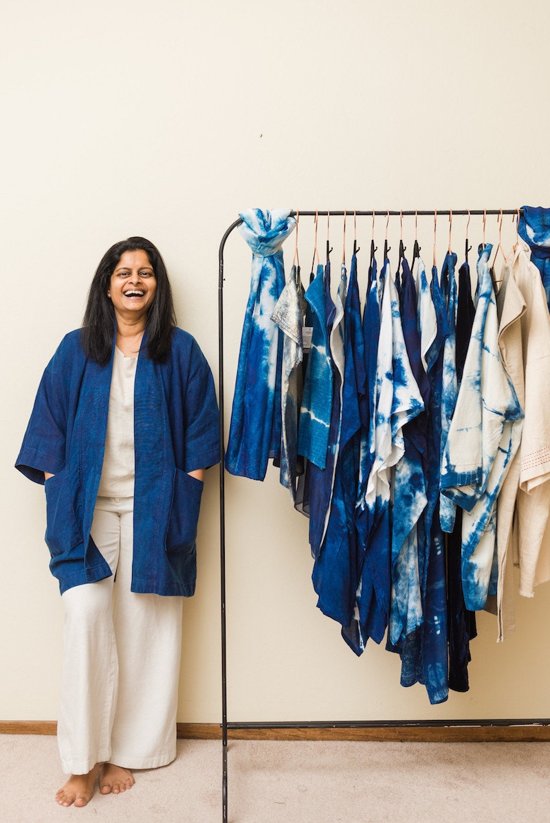 Rajni posing with a clothing rack of her items