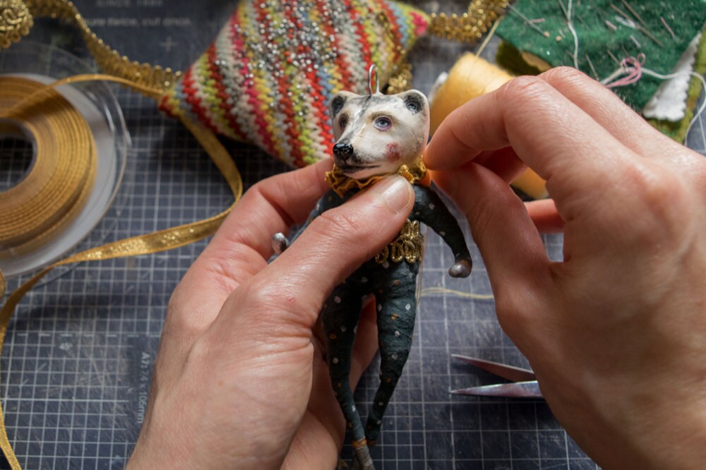 Kayleigh sews a ruffled collar onto her bear ornament